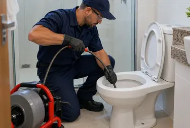 Técnico realizando desentupimento de vaso sanitário em uma casa.